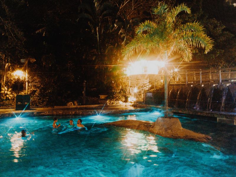Pessoas na piscina iluminada durante a noite no Parque das Fontes, no Rio Quente