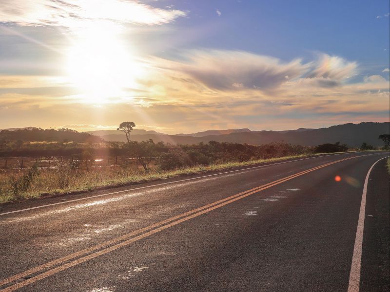 Estrada em Goiás com o sol se pondo no horizonte